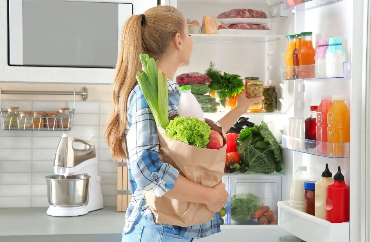 girl fills the fridge with groceries