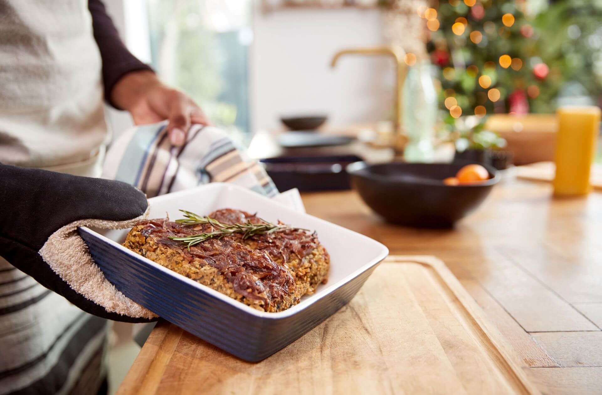 Close Up Of Man Taking Vegetarian Nut Roast Out Of Oven For Christmas Dinner